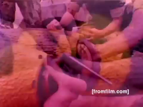 The still from the 'USMC Aviation Ordnance enlistment film' showcases a hands-on scene involving military personnel mounting ordnance, including missiles and bombs, onto aircraft. The aircraft depicted likely include F-4 Phantoms, AH-1 SuperCobras, an FA-18, and a Harrier, illustrating the 'Ordnance Option' for enlistment. The color has been re-rendered and corrected to enhance visibility, highlighting the precision and teamwork involved in military ordnance operations.