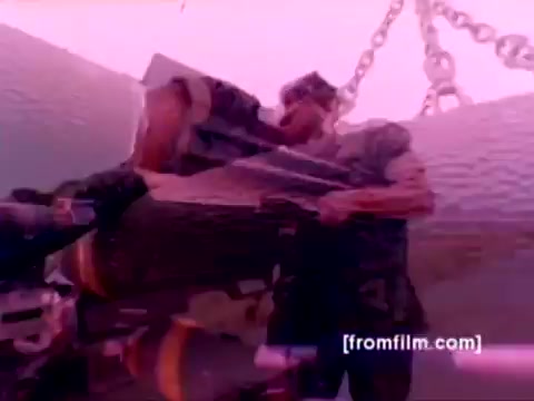 The still from the 'USMC Aviation Ordnance enlistment film' depicts a Marine personnel working on mounting ordnance, likely missiles or bombs, on military aircraft. The scene features elements such as an F-4 Phantom, AH-1 Super Cobra, FA-18, and a Harrier, showcasing the ordnance option available for enlistment. The color correction enhances visibility, revealing details of the aircraft and the ordnance being handled, while conveying a sense of the critical tasks involved in aviation ordnance operations within the Marine Corps.