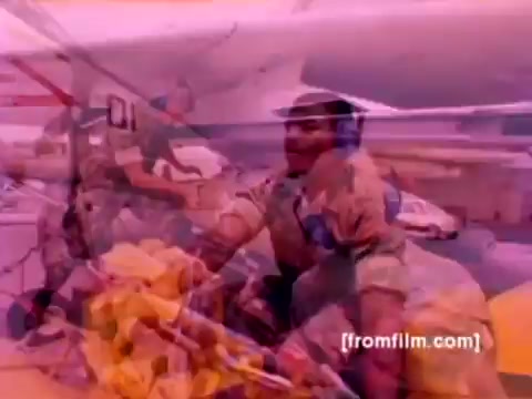 The still from the 'USMC Aviation Ordnance enlistment film' features a vivid scene depicting Marine Corps personnel engaged in ordnance operations. In the background, iconic aircraft like F-4 Phantoms, AH-1 SuperCobras, an FA-18, and a Harrier are visible. The focus is on the process of mounting missiles and bombs onto these aircraft, showcasing the technical and operational aspects of aviation ordnance. The color correction on this 16mm negative enhances the imagery, providing a more dynamic representation of the activity. The lack of sound adds a visual intensity, emphasizing the precision and dedication involved in the ordnance profession within the Marine Corps.