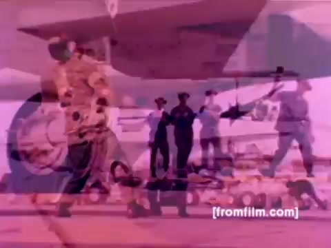 The still depicts a Marine Corps scene showcasing various aircraft, including F-4 Phantoms, AH-1 SuperCobras, an FA-18, and a Harrier. It captures ordnance personnel mounting missiles and bombs onto these aircraft, emphasizing the technical and operational aspects of aviation ordnance. The color appears muted and requires correction to enhance clarity and vibrancy, providing a more accurate representation of the scene. Overall, the image reflects the precision and teamwork involved in preparing military aircraft for operations.