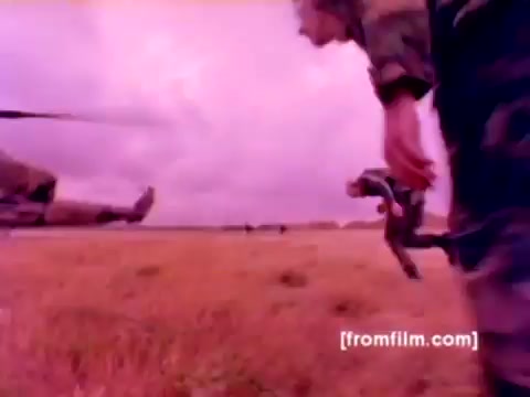 The still from the 'USMC Aviation Ordnance enlistment film' showcases Marine Corps personnel in action, prominently featuring F-4 Phantoms, AH-1 SuperCobras, an FA-18, and a Harrier aircraft. Soldiers are depicted mounting ordnance, such as missiles and bombs, highlighting the ordnance option for enlistment. The color correction of the 16mm negative would enhance the visual clarity and detail, making the military equipment and personnel more vivid and impactful against the backdrop of an operational environment.