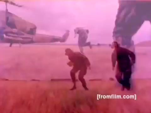 The still from the 'USMC Aviation Ordnance enlistment film' features military personnel and aircraft. In the background, F-4 Phantoms, AH-1 SuperCobras, an FA-18, and a Harrier are visible. Service members are engaged in mounting ordnance, including missiles and bombs. The 16mm negative exhibits a color tint, likely requiring enhancement for clearer, more accurate representation of the military environment and equipment. The overall scene evokes a sense of action and precision associated with Marine Corps aviation operations.