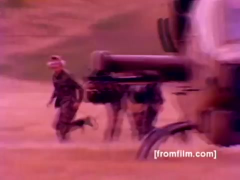 The still from the 'USMC Aviation Ordnance enlistment film' showcases a dynamic scene featuring Marines in camouflage uniforms running toward an AH-1 Super Cobra helicopter. In the background, you can see advanced military aircraft such as F-4 Phantoms, an FA-18, and a Harrier. The focus is on the ordnance operations, highlighting the mounting of missiles and bombs onto the aircraft. The overall color rendition from the 16mm negative appears muted, and enhancing it could reveal a richer palette indicative of military aviation contexts.
