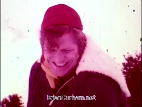 The still from 'Campbell's Soup - The Manhandlers' features a smiling man wearing a red beanie and a jacket with a fur collar. The background appears to be snowy, contributing to a cheerful and lively atmosphere. The scene encapsulates a fun and light-hearted vibe, likely aligned with the playful themes of the song performed by Frankie Laine.