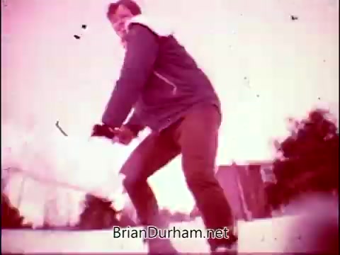 The still shows a man in a sporty outfit, poised as if skating or engaging in a dynamic activity. The colors are muted, with a pinkish hue dominating the scene, likely indicative of the film's age or processing. This image captures the lively spirit associated with the theme song by Frankie Laine for 'Campbell's Soup - The Manhandlers.'