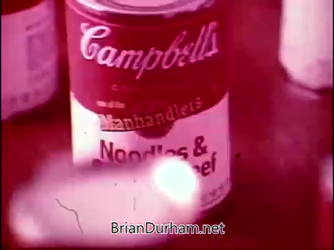 The 16mm still features a prominently displayed can of Campbell's Soup, specifically labeled 'Noodles & Beef,' from the commercial 'The Manhandlers' featuring the theme song by Frankie Laine. The image likely captures the essence of mid-20th century advertising, emphasizing the product in a colorful, stylized manner.