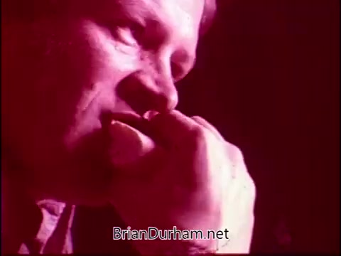 The still from 'Campbell's Soup - The Manhandlers' features a close-up of a man's face, capturing an intense moment as he appears deep in thought or concentration. The colors are saturated, predominantly in shades of red, adding a dramatic tone. This segment is likely linked to the theme song by Frankie Laine, conveying an emotional or narrative depth related to the characters or theme of the piece.