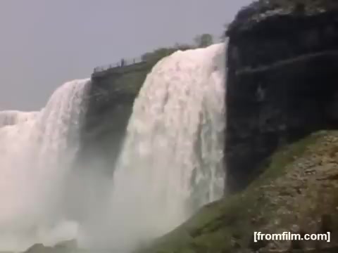 The still captures a scenic view of Niagara Falls, showcasing the powerful cascades of water. The rushing falls, framed by rocky cliffs, highlight the natural beauty of the area. This moment reflects a nostalgic era, emphasizing the majesty of the falls as a natural landmark during the late 1940s.