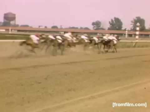 The still from 'Home Movies: Rochester/Niagara Falls 1948-1950' captures a dynamic scene of a horse race, depicting multiple horses galloping down a dirt track. The riders, dressed in white, are racing against one another, with a backdrop that hints at a vibrant atmosphere. The pastel coloring of the film adds a nostalgic feel, reflecting the era of the late 1940s.
