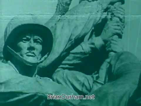 The still features a close-up of a statue depicting military figures, likely celebrating or honoring veterans. The soldiers are shown with serious expressions and military gear, emphasizing their bravery and dedication. The image has a vintage quality, typical of 1960s PSA (Public Service Announcement) material, and conveys a message of respect and remembrance for veterans.