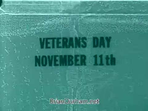 The still features the text 'VETERANS DAY' prominently displayed above 'NOVEMBER 11th.' The overall color tone is a light blue, giving it a vintage feel consistent with 1960s public service announcements. The simple design emphasizes the importance of the date, likely intended to promote awareness of Veterans Day.