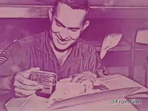 The still from the 1968 PSA 'Mail Early to Your Soldier' depicts a serviceman seated at a table, smiling as he opens a package. He appears engaged and pleased, suggesting a moment of connection and joy amidst the challenges of military service. The setting conveys a sense of warmth, highlighted by the colors and nostalgic tone typical of the era. The focus on mail emphasizes the importance of communication and support for soldiers stationed overseas, especially during the holiday season. The voice-over stresses the urgency and significance of sending gifts on time to ensure a Merry Christmas for servicemen.