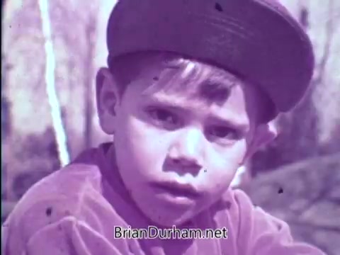 The still from the 1967 'Prevent Blindness PSA' features a young boy wearing a cap, looking directly at the camera with a serious expression. The image, likely faded and with a purple tint, conveys a sense of concern about vision health. The accompanying voiceover discusses the importance of detecting amblyopia (lazy eye) in children, emphasizing that early intervention can help prevent blindness. The ad aims to raise awareness about children's eye health, highlighting that one in twenty preschoolers have eye problems.