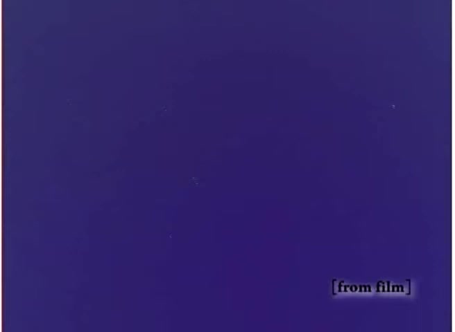 The still appears to be a monochromatic image with a deep purple background, labeled '[from film]' in the bottom right corner. It lacks any visible subjects or text, making it abstract and possibly a frame from a film reel without significant content or action.