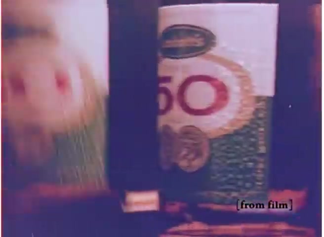 The still from the 'Labatt beer commercial' features two beer cans prominently displayed. One can is mostly visible, with bold red lettering indicating the number '50.' The design incorporates colorful graphics typical of the 1970s style. The shot’s overall tone is slightly faded, characteristic of a 16mm film negative, evoking a nostalgic feel of vintage advertising from that era.