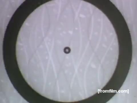 The still features a circular black frame with a small central dot, set against a textured background displaying wavy patterns. This simplistic design reflects the stylistic elements of 1950s animation, likely serving as a visual focus for promoting Caloric gas appliances. The imagery suggests a playful yet functional aesthetic typical of UPA's approach in advertising, emphasizing innovation in home cooking technology.
