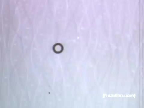 The still features a simple, stylized design typical of UPA animation from the 1950s. It showcases a small, black circular shape against a soft, textured background that appears to be made of swirling lines. This minimalistic approach aligns with the commercial's focus on Caloric gas ovens and ranges, emphasizing clarity and modernity in appliance design. The overall aesthetic reflects the mid-century style prevalent in advertising during that era.