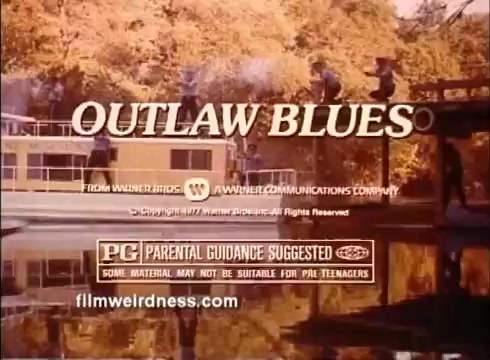 The still features the title 'OUTLAW BLUES' prominently displayed in a stylized font, set against a backdrop of a scenic lake scene with trees. It references the film's production company and includes a parental guidance advisory, indicating that the content may not be suitable for younger audiences. The overall aesthetic suggests a classic feel typical of 1970s cinema.