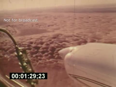 The still from 'Sixty Second Spot' captures a moment in the creation of a 7-Up commercial, showcasing an aerial view of clouds from an aircraft. The vintage 16mm film style evokes a sense of nostalgia for the mid-1970s. This particular scene, timed at 1 minute and 29 seconds, signifies the exploration of production elements, from scripting to filming, offering viewers insight into the behind-the-scenes process of television advertising. The 'Not for broadcast' label indicates it was likely intended for internal use rather than public viewing.