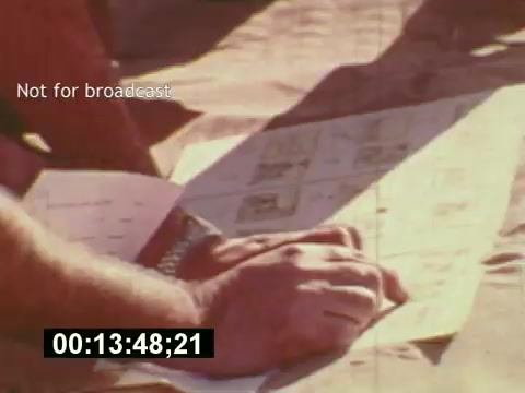 The still from **'Sixty Second Spot'** shows a close-up of hands examining a storyboard or script related to a 7-Up commercial. The setting appears to be outdoors, possibly on a production set, capturing a moment in the creative process. The timestamp at the bottom indicates it's part of the film's progression. This film highlights the behind-the-scenes efforts in the making of a TV commercial, from conceptualization to execution in the mid-1970s.