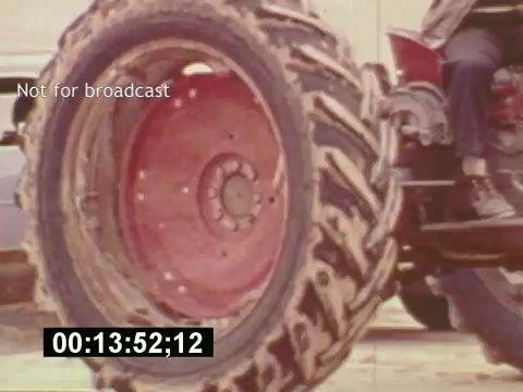 The still from 'Sixty Second Spot' captures a close-up of a large, muddy tractor tire, highlighting its texture and rugged design. The scene likely represents part of the behind-the-scenes footage for a 7-Up commercial, showing the vehicle's role in filming. Text overlays indicate it’s not for broadcast, and a timecode is visible at the bottom, suggesting it's an unedited clip. The overall aesthetic reflects the mid-1970s film style, emphasizing the gritty and authentic process of creating television advertising.