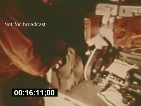 The still from 'Sixty Second Spot' captures a behind-the-scenes moment in the creation of a 7-Up commercial from the mid-1970s. It shows crew members working with film equipment, highlighting the production process from scripting to casting and filming. The frame features a clear label stating 'Not for broadcast,' indicating that this is an exclusive look at the making of the commercial, rather than a finalized product. The timestamp suggests it's part of a longer narrative exploring the intricacies of commercial filmmaking during that era.