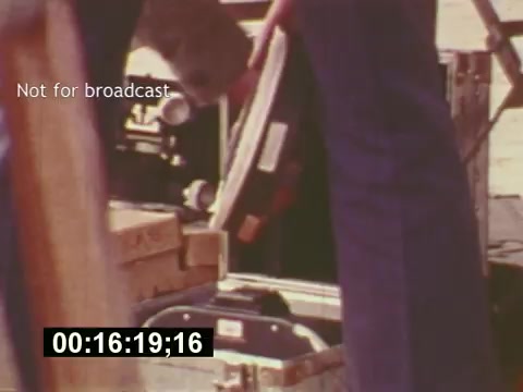 The still from 'Sixty Second Spot' captures a behind-the-scenes moment in the making of a 7-Up commercial from the mid-1970s. You see crew members handling equipment, emphasizing the production process—highlighting the intricate details from script development to casting and filming. A timestamp indicates it's 16 seconds into the scene, offering a glimpse into the operational atmosphere of creating a television ad during that era. The 'Not for broadcast' label suggests it's part of a documentary or promotional material rather than the final product.