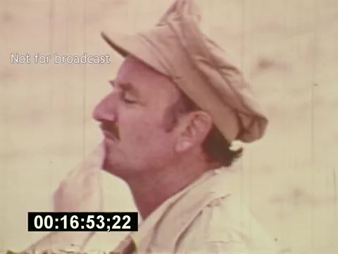 The still from 'Sixty Second Spot' captures a moment during the production of a 7-Up commercial from the mid-1970s. It features a man in profile, wearing a light-colored jacket and a cap, seemingly deep in thought or contemplation. The scene may emphasize the creative process involved in filmmaking, as this film chronicles the journey from scripting to casting and filming the commercial. The timestamp and 'Not for broadcast' label suggest its use for reference rather than public viewing.