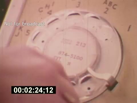 The still from 'Sixty Second Spot' features a close-up of a rotary dial phone, emphasizing the era's vintage technology. The scene captures the process of creating a 7-Up commercial, likely illustrating a moment of planning or communication, integral to the film's exploration of advertising in the mid-1970s. The 'Not for broadcast' watermark indicates it’s a behind-the-scenes shot rather than a final product.