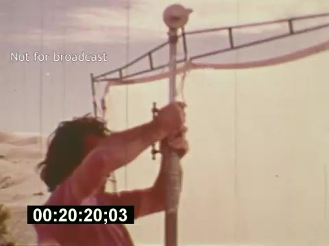 The still from 'Sixty Second Spot' depicts a behind-the-scenes moment in the creation of a 7-Up commercial from the mid-1970s. It shows a crew member adjusting equipment on set, highlighting the technical process involved in filming. The image encapsulates the filmmaking experience, focusing on the meticulous details of production as the commercial evolves from script to screen. The overlay note 'Not for broadcast' indicates that this is likely a test or behind-the-scenes footage, offering insight into the commercial-making process.