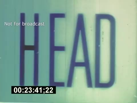 The still from 'Sixty Second Spot' features the word 'HEAD' prominently displayed, indicating a segment title or theme related to the creative process of a 7-Up commercial from the mid-1970s. The text is visually striking against a light background, which could suggest a focus on key aspects of the advertisement's development, including script, casting, and filming. The film offers a behind-the-scenes look at commercial production, culminating in the final advertisement.