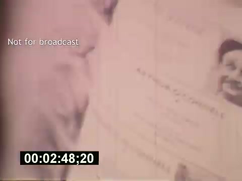 The still captures a moment from the film 'Sixty Second Spot,' showcasing the behind-the-scenes process of creating a 7-Up commercial in the mid-1970s. It appears to depict a casting document, possibly featuring a photograph of an actor or spokesman, alongside text related to the commercial's production. The note 'Not for broadcast' suggests it's intended only for internal use. A timestamp at the bottom indicates the specific moment within the film. Overall, it offers a glimpse into the creative journey of advertising during that era.