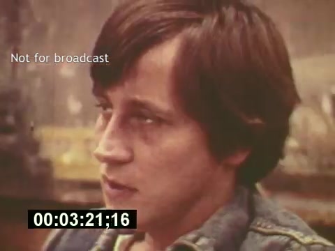 The still from 'Sixty Second Spot' captures a candid moment during the production of a 7-Up commercial from the mid-1970s. It features a young man, likely an actor or crew member, deep in thought as he prepares for his role. The visual quality reflects the era, with a warm, faded color palette typical of 16mm film. The text 'Not for broadcast' indicates that this is behind-the-scenes footage, emphasizing the documentary aspect of how commercials were crafted, from script development to casting and filming. The timestamp suggests it's a critical moment in the production process.