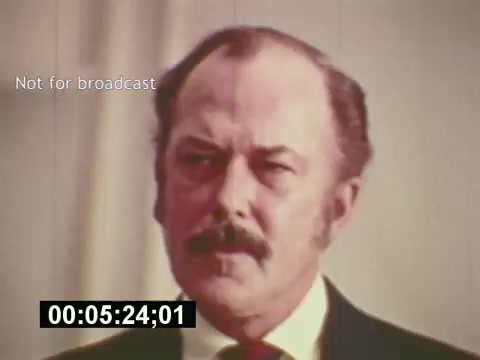 The still from 'Sixty Second Spot' features a man with a mustache and serious expression, capturing a moment likely related to the casting or production process of a 7-Up commercial in the mid-1970s. The film explores the steps involved in creating a TV commercial, showcasing elements such as scripting, casting, and filming. This particular moment is time-stamped, indicating it's part of a sequence before the commercial is presented. The context offers insight into the behind-the-scenes of advertising during that era.