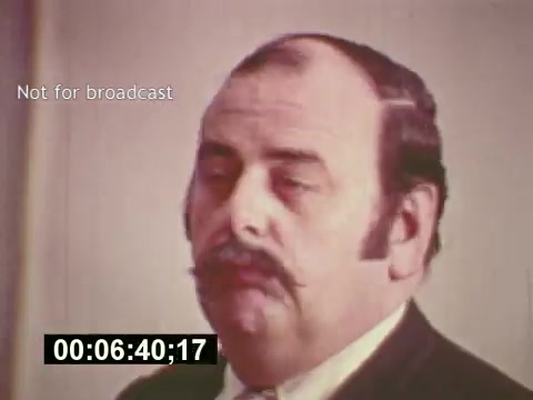 The 16mm still from 'Sixty Second Spot' captures a moment during the production of a 7-Up commercial, likely depicting a key figure involved in the project. The film documents the entire process of creating the commercial, from script development to casting and filming. This scene emphasizes the behind-the-scenes work that goes into advertising in the mid-1970s, showcasing the creative and logistical efforts in the industry at that time. A timestamp on the image suggests it is from a specific moment within the film.