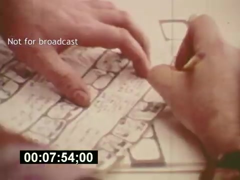 The still from 'Sixty Second Spot' captures the behind-the-scenes process of creating a 7-Up commercial from the mid-1970s. It features a close-up of hands meticulously working on a storyboard, outlining scenes and dialogue. The image highlights the detailed planning that goes into commercial production. A timestamp at the bottom indicates it's part of a documentary aspect, emphasizing the craft and creativity involved in advertising during that era. The text 'Not for broadcast' suggests it's a production still, intended for educational or archival purposes.
