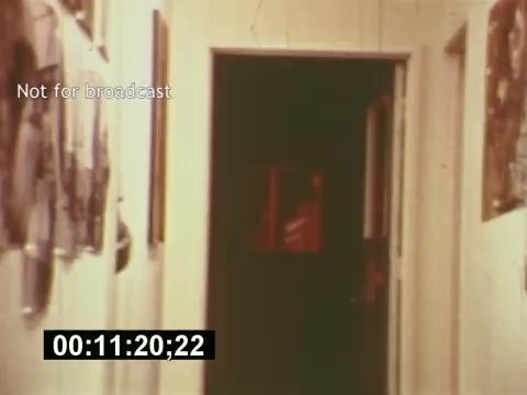 The 16mm still from 'Sixty Second Spot' depicts a hallway lined with photographs and artwork, creating a nostalgic, mid-1970s atmosphere. The scene captures a moment in the film that examines the process of creating a 7-Up commercial, showcasing elements like scriptwriting, casting, and filming. The text 'Not for broadcast' indicates that this is likely an unused or archival clip. The timer shows a specific moment in the film, emphasizing its documentary format.
