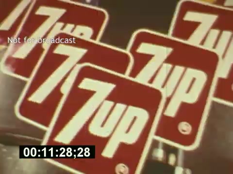 The still from 'Sixty Second Spot' features a vibrant display of 7-Up branding, showcasing multiple 7-Up signs prominently. This moment captures the essence of advertising in the mid-1970s, emphasizing the creativity and design elements involved in producing a TV commercial. The film details the journey from scripting to casting and filming the final commercial, providing a behind-the-scenes look at the process. The focus is on the iconic brand, highlighting its playful and refreshing image.