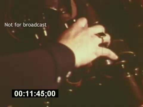 The still from 'Sixty Second Spot' captures a behind-the-scenes moment of the filmmaking process for a 7-Up commercial from the mid-1970s. It features a close-up of a hand adjusting camera equipment, emphasizing the technical side of production. The overlay text 'Not for broadcast' indicates that this is a private or unreleased clip, while the timestamp suggests the scene is part of the film's exploration of the entire commercial creation process, including scripting, casting, and filming.