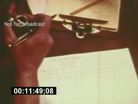 The still features a close-up of a person's hand holding a pen above a clipboard, where they are writing on a sheet of paper. The paper appears to contain notes or a list, possibly related to the production process of the 7-Up commercial. The timestamp at the bottom indicates the film's timing, and the caption 'Not for broadcast' suggests it's a behind-the-scenes or production-related shot. Overall, this moment captures the meticulous planning and organization involved in creating a television commercial from the mid-1970s.