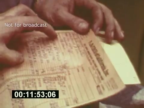 The still captures a close-up of hands holding a document, likely related to the production of a 7-Up commercial. The paper appears to be a script or production note, reflecting the behind-the-scenes process of creating a TV ad from the mid-1970s. The watermark 'Not for broadcast' indicates this material is meant for internal use. The timestamp at the bottom suggests a specific point in the film, emphasizing its documentary nature. Overall, it highlights the meticulous planning involved in commercial creation.
