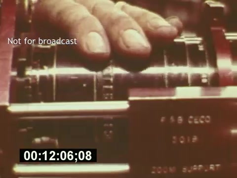 The still from 'Sixty Second Spot' captures a close-up of a hand operating a film editing machine, likely signifying a critical moment in the production process of a 7-Up commercial. The image is set against a backdrop suggesting a vintage filmmaking environment typical of the mid-1970s. The frame includes a timestamp and a note indicating it's not for broadcast, emphasizing its behind-the-scenes nature as it documents the crafting of television advertising from script to screen.