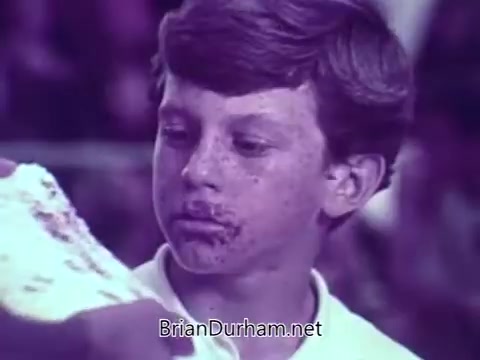 The still features a young boy with a smudged face, likely covered in chocolate or candy residue, indicating he has just enjoyed some M&M's. His expression is one of delight or surprise, creating a playful tone that fits the animated theme of the commercial. The scene likely captures a lighthearted moment in the larger context of M&M's promoting their candies through fun and relatable visuals.