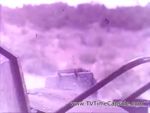 The still from 'Have a Coke and a Smile - Coke Adds Life' features a dusty, outdoor scene, likely from a moving vehicle. The blurred landscape indicates motion, evoking a sense of adventure or journey. The color palette appears faded, typical of 16mm film, contributing to a nostalgic feel. The image suggests a carefree lifestyle associated with enjoying Coca-Cola.