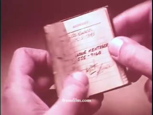 The still features a close-up of a person's hands holding a small notebook or wallet. The page visible displays handwritten information, likely a contact or identification detail, with a name and phone number visible. The image’s warm tones suggest it’s from an older film, consistent with the early 1970s. This could be a part of a promotional segment highlighting the investigative work of Chris Borgen as a crime reporter.