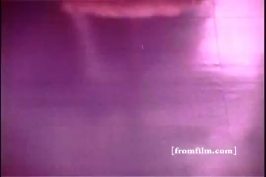 The still from 'Formica Floor Shine' showcases an abstract, reflective surface, likely a shiny floor. The hue is predominantly purple, creating a surreal and stylized atmosphere. Subtle textures and patterns are visible, suggesting motion or liquid, blending aesthetics with an everyday environment. The graininess typical of 16mm film adds to its vintage feel.