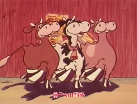The still features three animated cows, each with distinct colors—two brown and one black-and-white. They are playfully arranged against a rustic barn background. The cows appear cheerful, possibly promoting the wholesome image of Land-O-Lakes margarine. The scene captures a lighthearted, cartoonish style typical of vintage commercials.