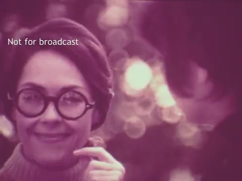 The still from the 'Pruf Spray Starch' commercial features a woman with short hair and round glasses, expressing a friendly demeanor while holding a finger to her chin. The background has a soft, blurred effect, typical of 1960s aesthetics, with warm, hazy lighting that creates a nostalgic atmosphere. The text 'Not for broadcast' is prominently displayed, indicating this image is intended for archival or reference purposes only.