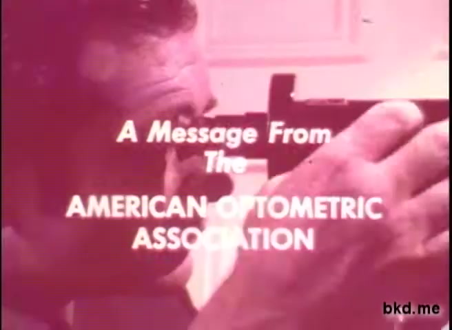 The still features a man focused on a device, likely an optometric tool, emphasizing the importance of eye care. The text, 'A Message From The AMERICAN OPTOMETRIC ASSOCIATION,' is prominently displayed, indicating an informative public service announcement from the 1970s aimed at promoting eye health awareness. The image has a vintage quality typical of 16mm film, with a slightly faded color palette.