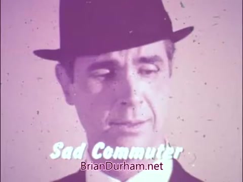 The still features a somber male figure, identified as the 'Sad Commuter,' wearing a hat and a subdued expression. The color palette has a faded, vintage quality typical of 60s/70s PSAs. This imagery likely conveys the grueling realities of commuting, relating to the campaign by the National Tuberculosis and Respiratory Disease Association before its rebranding in 1973. James Noble's portrayal suggests a reflection on health challenges, emphasizing the emotional weight of respiratory disease awareness during that era.